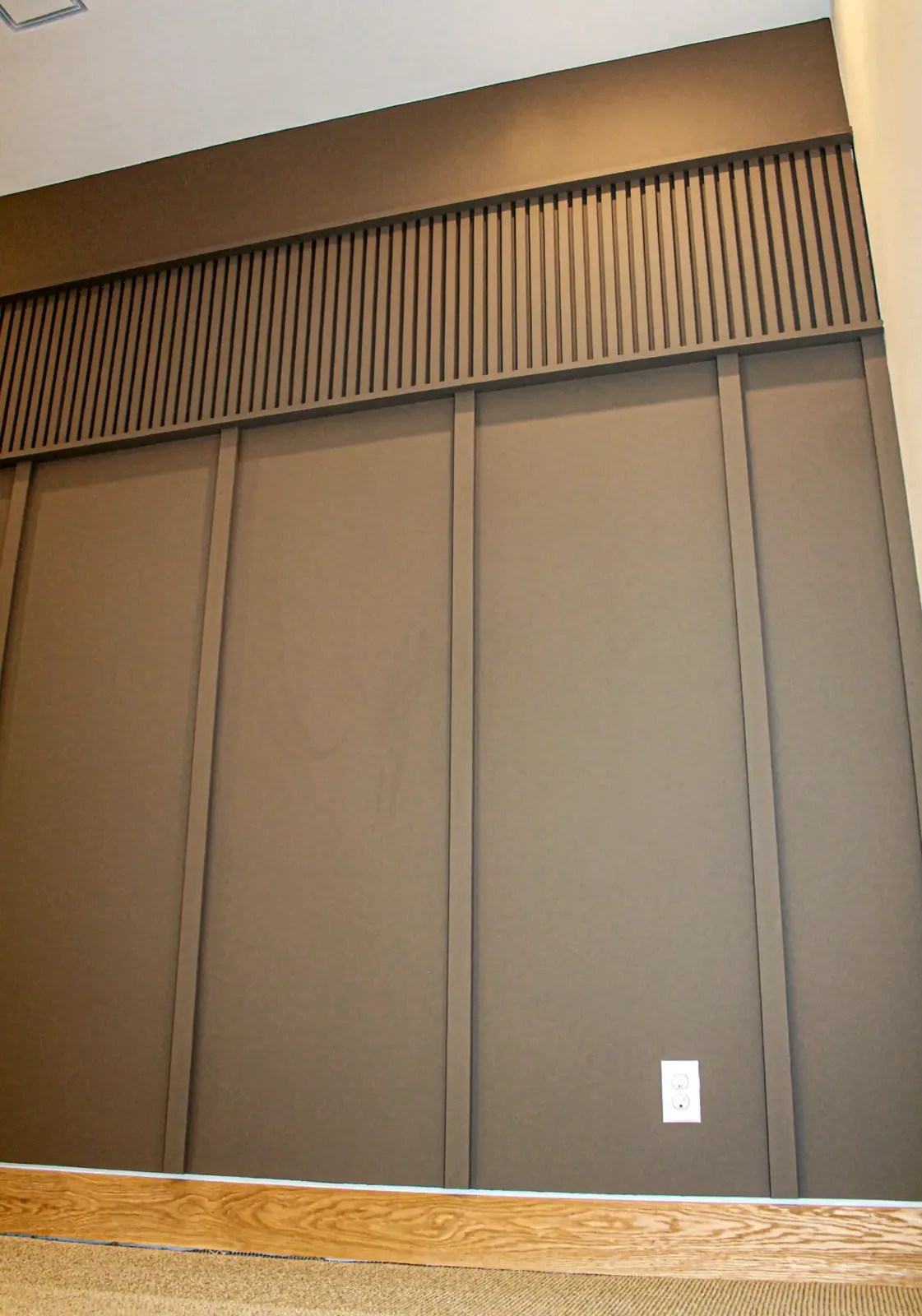 Painted board and batten wall with a horizontal band of narrow vertical slats running above it