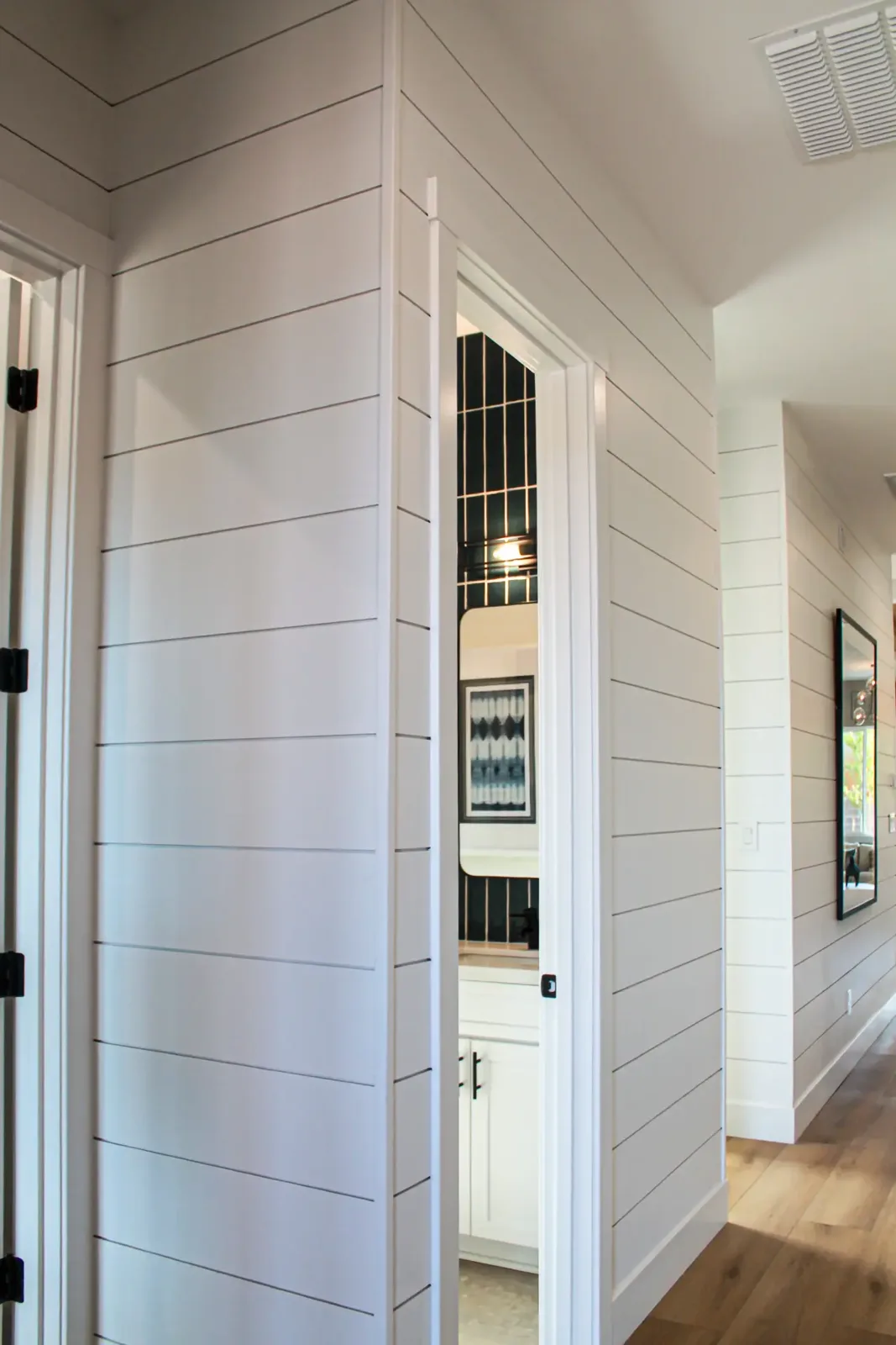 Hallway walls clad in white shiplap with painted casing around an open doorway